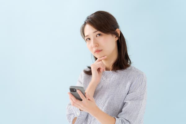 大人の歯を矯正する場合にかかる費用をスマホで調べる女性