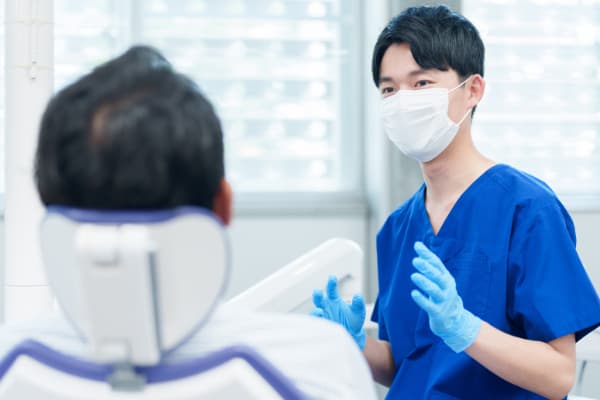 歯の矯正にかかる費用の負担を抑える方法について歯科医師に相談する男性