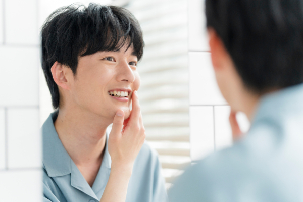 叢生を治療したはを鏡で確認して嬉しそうな男性
